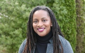 Dr. Lauren Eldridge Stewart, in a grey jacket, smiles at the camera 