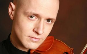 Photo portrait of Moni Simeonov, violinist, closeup, looking at camera with thoughtful expression on face