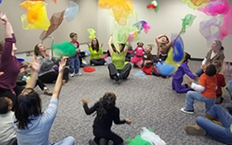 children and parents al play with colorful scarves in a class