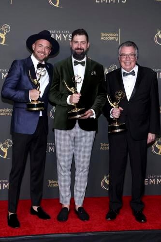 three men backstage, smiling, celebrating with the Emmy Award trophy they each hold.