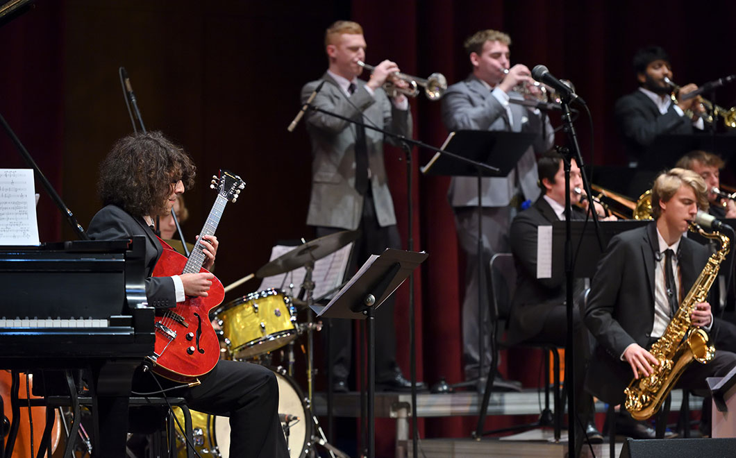 Jazz Orchestra members performing on stage of the Fairchild Theatre, guitar, piano, trumpets and saxophone instrumentalists