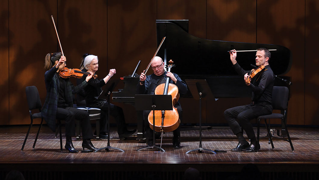 Chamber music group on stage performing, pianist, violinist, cellist and violist.