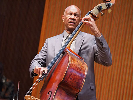 jazz bassist John Clayton, performance photo, eyes closed in concentration, performing with hands on bass