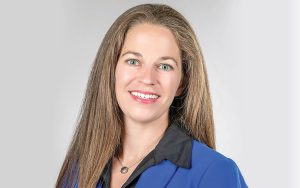 Johanna Frymoyer, Portrait, smiling and looking at camera, wearing a blue blazer with necklace