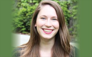 Anabel Maler, smiling looking at camera with green foliage in background