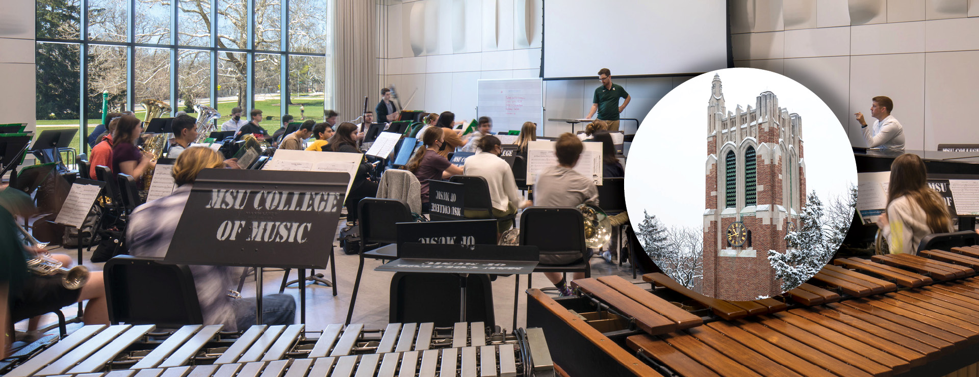 Image of symphony band rehearsing in large hall. Marimba instruments in foreground and several students with instruments led by conductor