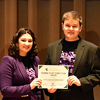 two people smile and hold a certificate