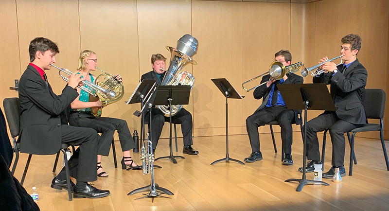 A group of five people play brass instruments on a stage
