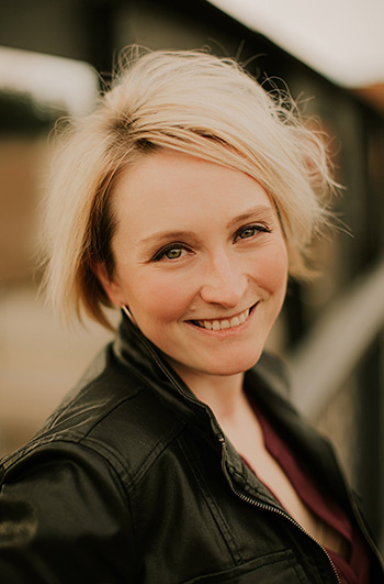 person with blond hair and black leather jacket, smiling