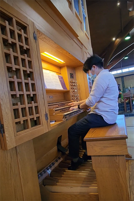 person seated at and playing a large organ in a church