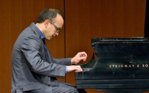 Faculty member Derek Polischuk seated, playing the piano.