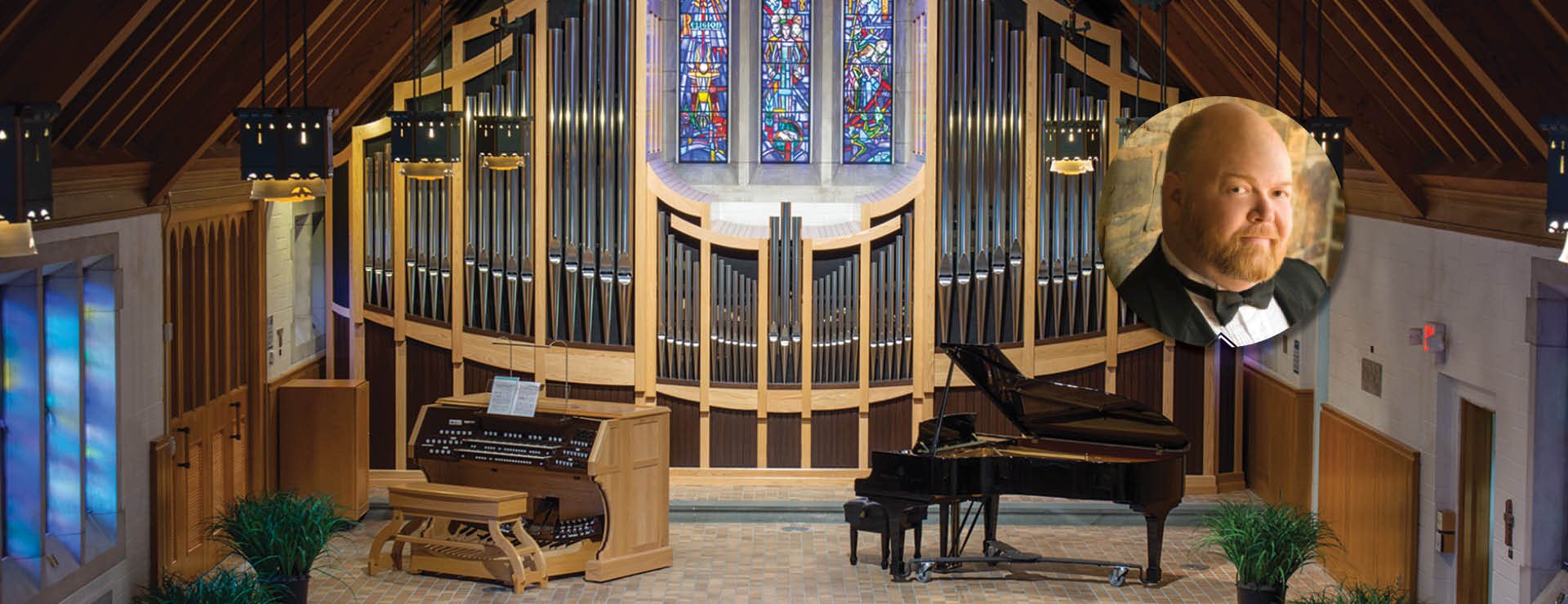 setting of the alumni memorial chapel stage with piano and organ instruments in the foreground, in the background are the pipes of the organ, and stained glass window at the top