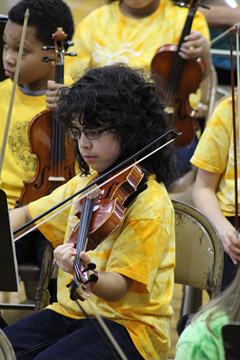 young person with glasses and yellow shirt playing violin