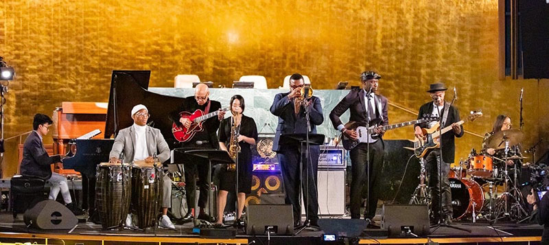 group of musicians performing on a stage with in front of a gold wall
