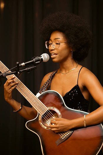 person playing acoustic guitar and singing into microphone
