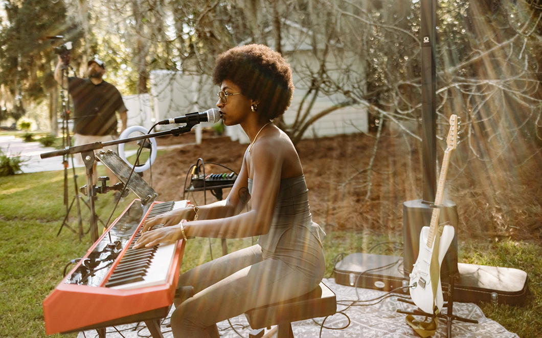 person playing orange electric keyboard and singing outdoors