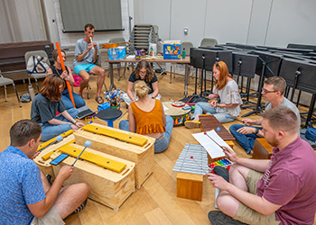 a group of people sitting on a floor while playing various musical instruments