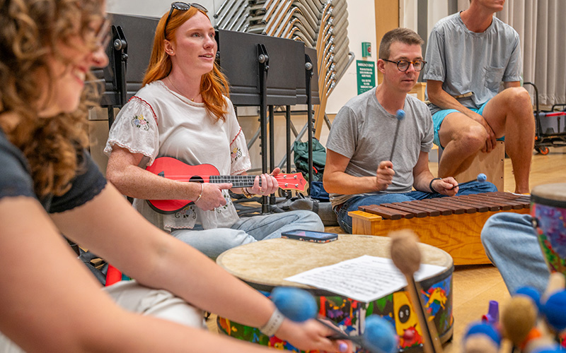 a group of people sitting on a floor while playing various musical instruments