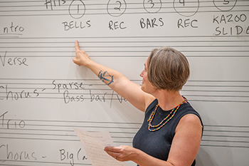 person points at a white board with music staff lines