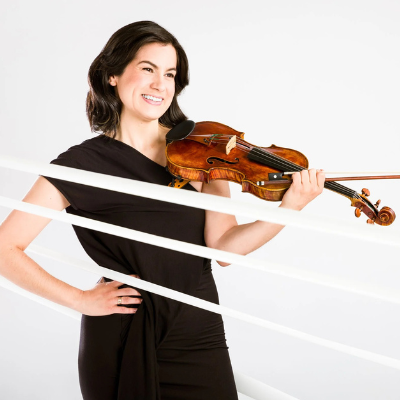 Photo portrait of Catherine-Cho, smiling and holding violin while looking away from the camera