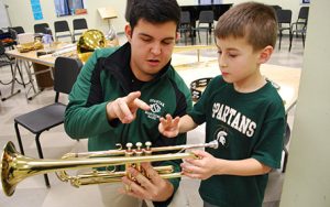 adult showing child how to hold a trumpet