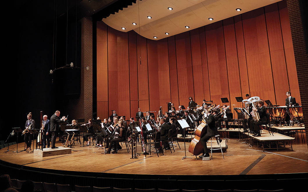 MSU Wind Symphony on the Cobb Great Hall stage of Wharton Center. Photo from stage left, musicians off to the right with the conductor directing the group
