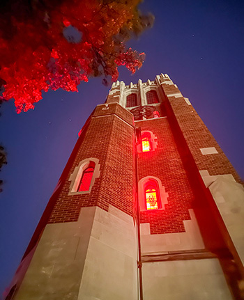 a tower is lit with bright lights that make the small windows glow orange