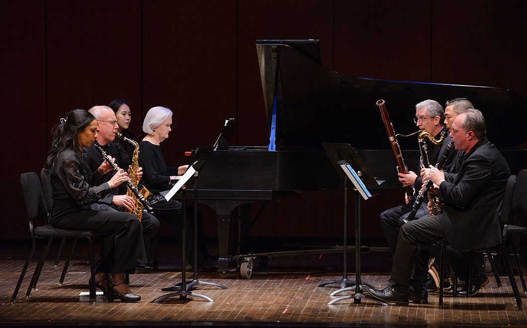 a woodwind and piano ensemble performs on stage