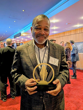 Person smiles while holding a trophy