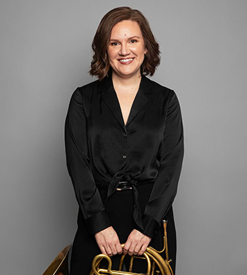 person standing, holding French horn