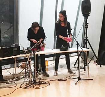 two people in an event space performing with a speaker and electronics