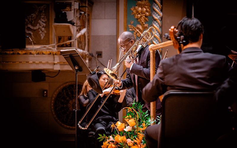 a person on stage performs on trombone
