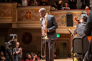 a person with a trombone on stage smiles at the audience