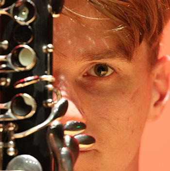 close up of person peering from behind a woodwind instrument