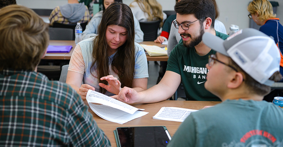 students help one another in a college classroom