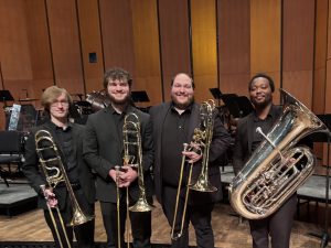 Image of the Leonidas Brass Quartet standing on a stage, holding their instruments.