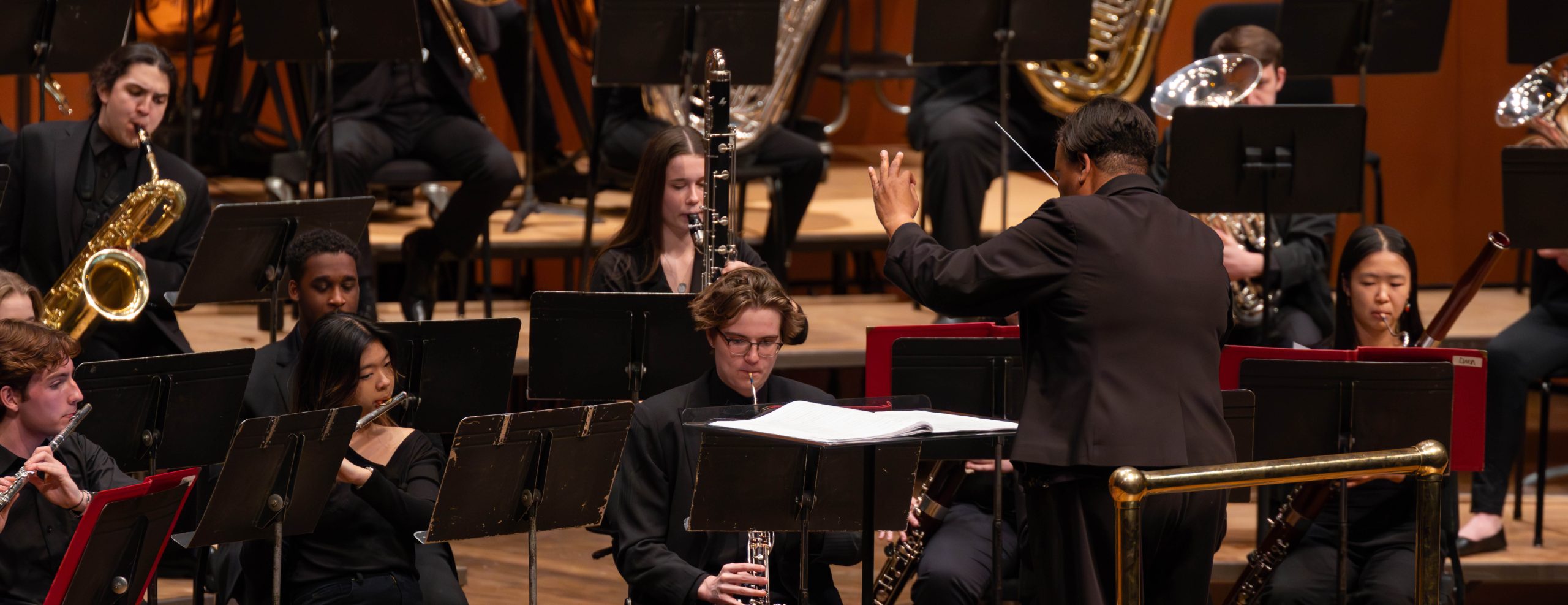 MSU Band Conductor holding baton while conducting MSU Band on stage.