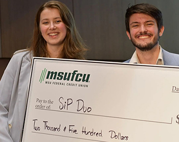 Duo holding up a large check from MSUFCU