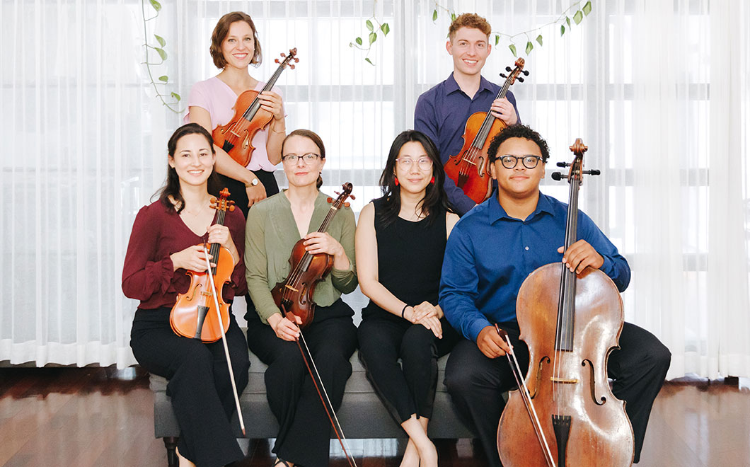 Group portrait of early music group, Ensemble Affect, with six musicians smiling and looking at camera and holding string instruments.