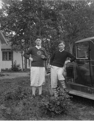 black and white image from 1928 of two people outdoors, one leaning against a car