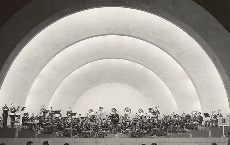 a large band shell behind a group of musicians on a stage