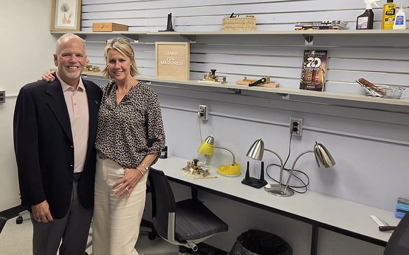 a couple stands in front of shelves and a thank you sign