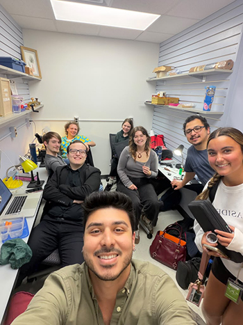 a group of eight people in a room with shelves on the walls